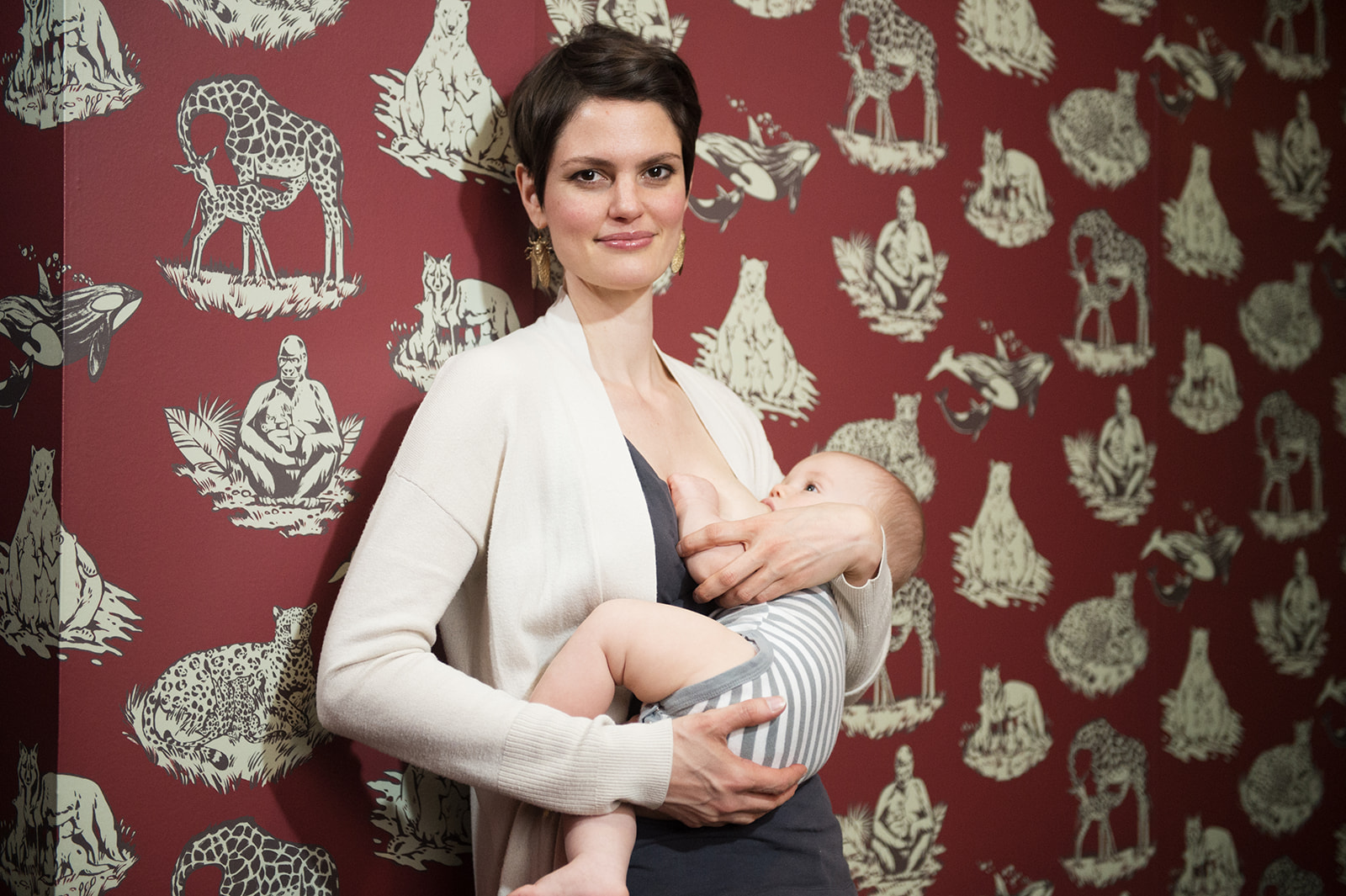 Artist Ashley Cecil nurses her son in a natural history museum breastfeeding room adorned with her nursing mammal wallpaper